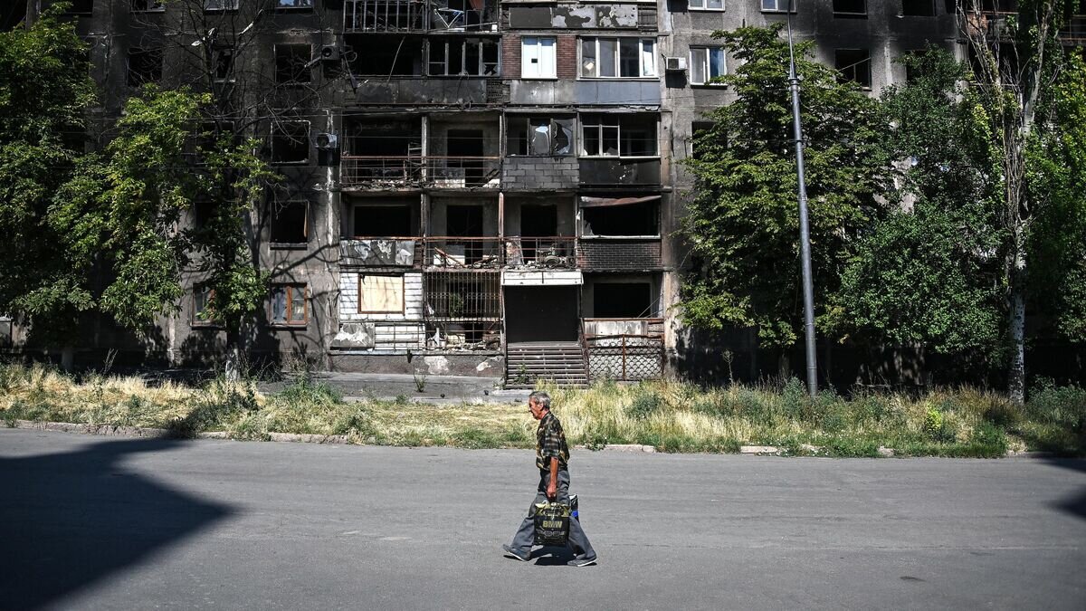    Мужчина проходит мимо жилого дома, разрушенного в результате боевых действий в Мариуполе© РИА Новости /