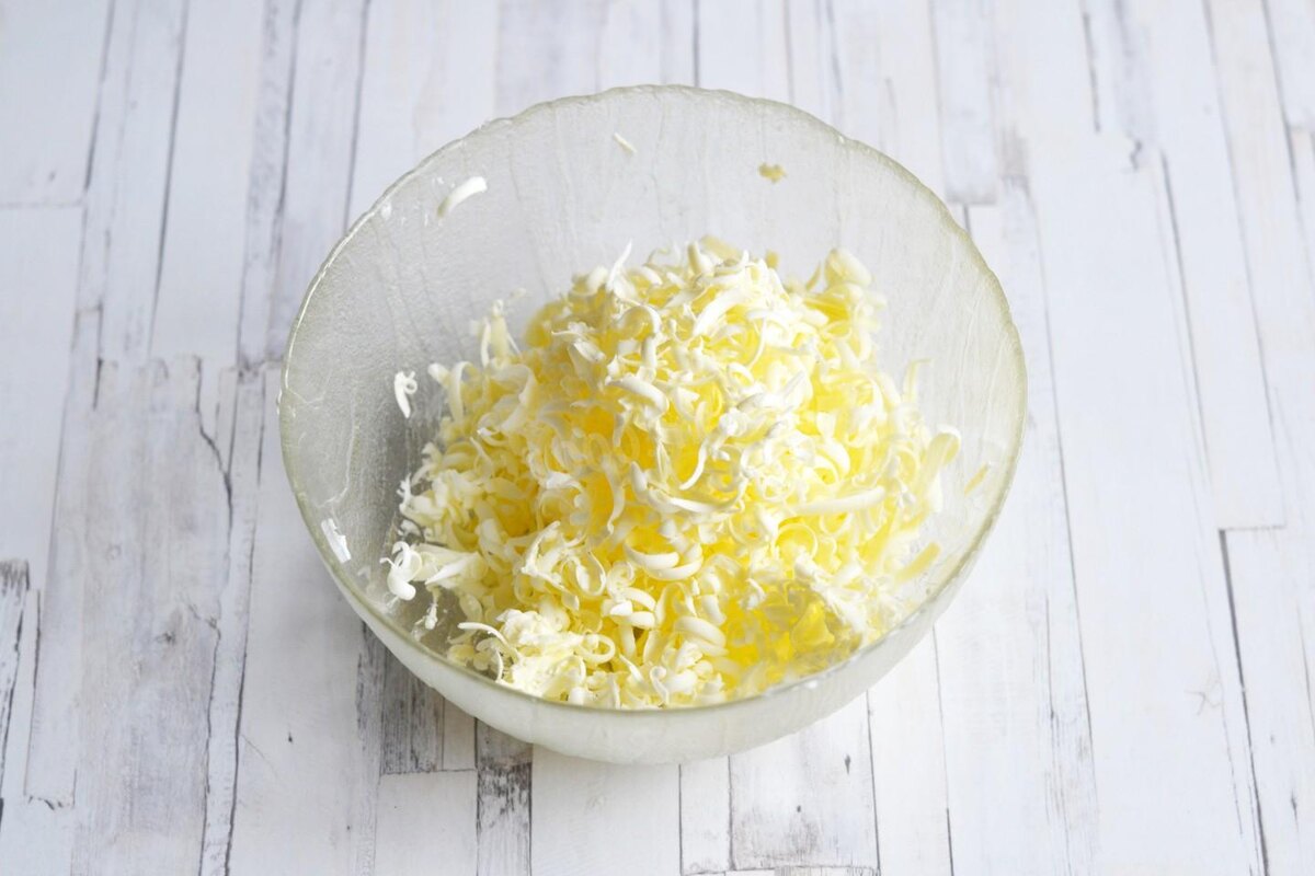 Предварительно замороженное масло натрите в миску на крупной терке.