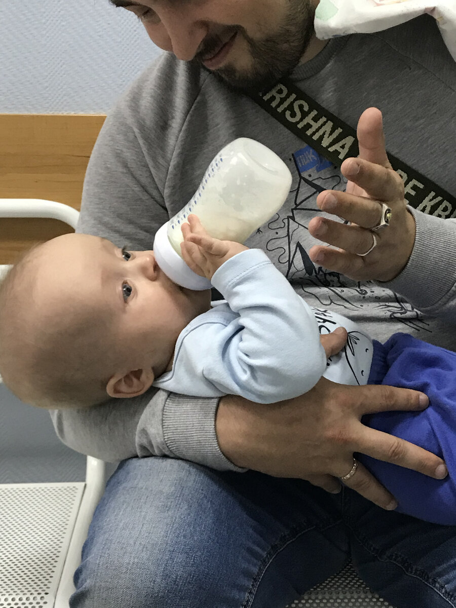 Голодный малыш вцепился в бутылочку после МРТ.