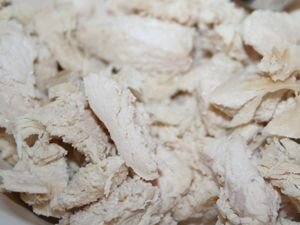    Промываем куриное филе под проточной водой и перекладываем его на разделочную доску. С помощью ножа срезаем хрящи, жир и возможные косточки. Затем выкладываем филе куском в кастрюлю и заливаем холодной водой так, чтобы жидкость полностью покрывала ингредиент. После закипания воды, шумовкой снимаем образовавшуюся от варки мяса пену. Куриный бульон немного солим и хорошо все перемешиваем столовой ложкой. Варим куриное филе в течение 25–35 минут на огне меньше среднего. Затем выключаем конфорку и достаем с помощью вилки куриный ингредиент.     Перекладываем филе на разделочную доску и с помощью ножа нарезаем куриное мясо на небольшие по величине кусочки. Перекладываем измельченное мясо в свободную миску. 