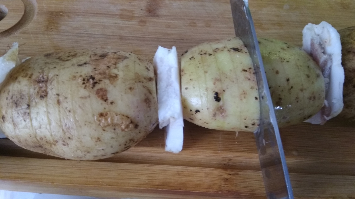 Далее ножом надрезаем картофель дольками до шампура, который ограничит прорез так, чтобы картофель не распался. Нужно нарезать, как можно тоньше, чтобы картофель пропёкся и пропитался маслом посильнее.