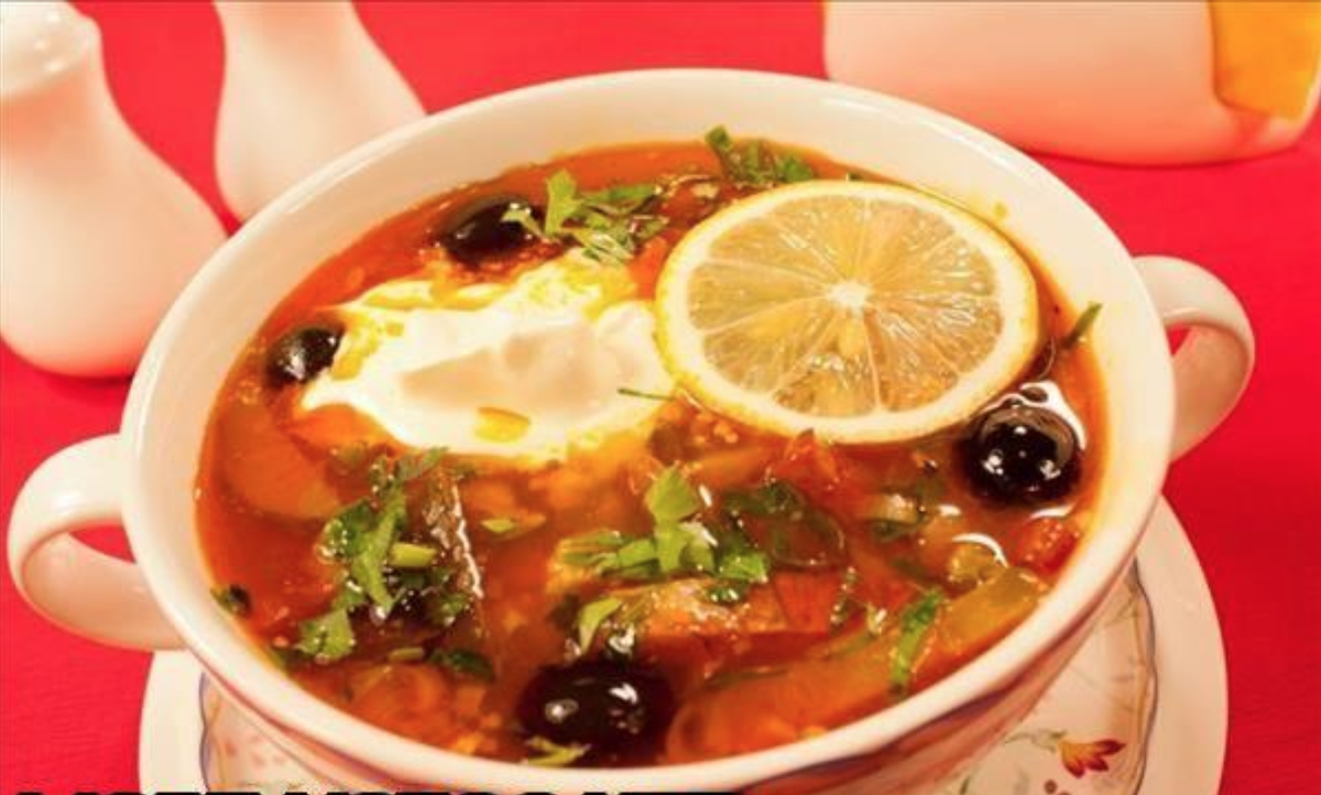 сливочное масло — 25 гр.
паста томатная — 35 гр.
копчёные рёбра — 0,3 кг.
оливки — 30—35 шт.
лук — 2 шт.
свинина/говядина на кости — 650 гр.
вода — 2,8 л.
растительное масло — 45 мл.
корнишоны — 6—8 шт.
петрушка — 0,5 пучка
ветчина, копчёная колбаса — по 150 гр.
лавр, перец-горох — по 3 шт.
каперсы — 60 гр.
лимон, сметана — по факту
смолотый чёрный перчик, соль — на свой вкус
Перед тем как приготовить вкусную солянку сборную мясную, возьмите все ингредиенты по списку. Суп, сваренный собственноручно в домашних условиях, получается наваристым и ароматным.

1. Итак, влейте воду в объёме по рецептуре в тару для варки. Отправьте внутрь рёбра с мясом. Дайте жидкости закипеть, снимайте пену.

2. В момент начала бурления поместите в кастрюлю 1 очищенную от шелухи луковицу. Засеките 2 часа, уваривайте ингредиенты на малой мощности.3. Примерно через 1 час 45 минут после начала томления отправьте внутрь лаврушку и перец-горох. Присыпьте солью на свой вкус.

4. После завершения варки вытащите рёбра с мясом, отделите от косточек и порубите. Лук выбросьте навсегда, сам бульон пропустите через пару слоёв марли.

5. Теперь порубите корнишоны тонкими кружочками. Колбасу с ветчиной измельчите брусочками не слишком крупно. Поместите компоненты вместе с растительным маслом в сковородку и жарьте 3 минуты. Влейте немного бульона, томите ещё 4 минуты.

6. Отдельно прожарьте вторую луковицу на сливочном масле, порубив её. Присыпьте перчиком, примешайте томатную пасту, протушите порядка трёх минут. Смешайте с колбасой, огурчиком и ветчиной. Введите эти компоненты в бульон.

7. Обратно верните в кастрюлю порубленное и отделённое от костей мясо. Маслины или оливки измельчите тонкими колечками, тоже примешайте в общую посуду. Уваривайте составляющие четверть часа, после чего введите каперсы.

8. Так как приготовить самую лучшую солянку сборную мясную проще простого, мы надеемся, что в домашних условиях у вас всё получилось! Дегустируйте соляночку с кусочками лимона, порубленной зеленушкой и сметаной.