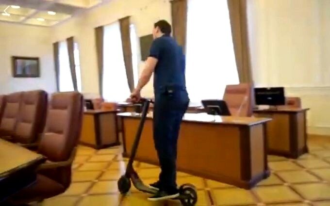 Алексей Гончарук на самокате в кабинете.