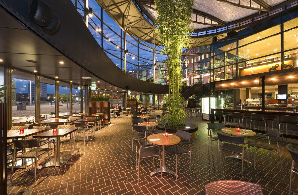 Круговой стеклянный фасад открывает прекрасный вид на бульвар. Естественный дневной свет создаёт внутри бара открытую и благоприятную атмосферу  