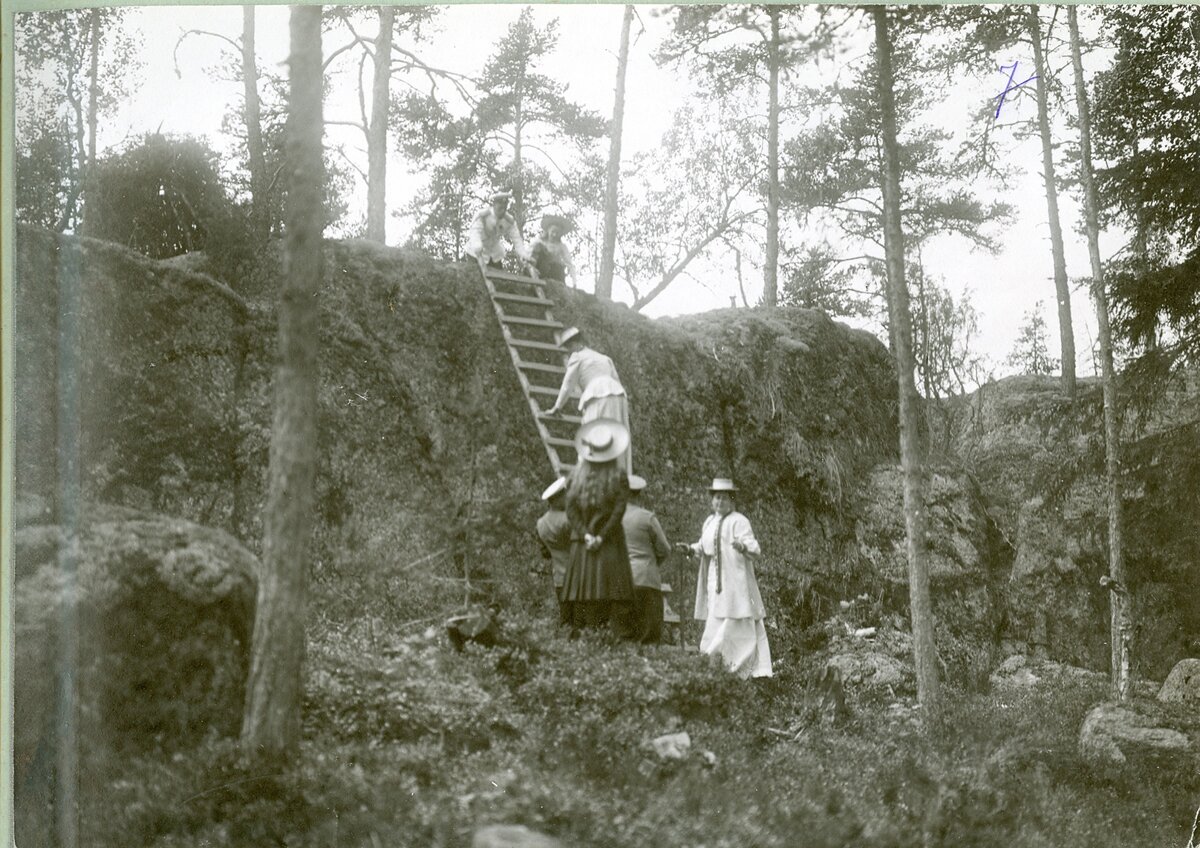 Прогулка по острову. Император Николай II (вверху, держит лестницу), вел. кн. Татьяна (рядом с ним), императрица Александра Федоровна (на лестнице), А. А. Вырубова, вел. кн. Ольга. Финские шхеры, 1909.