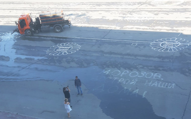 На фото изображены остатки рисунков и поливомоечный автомобиль.