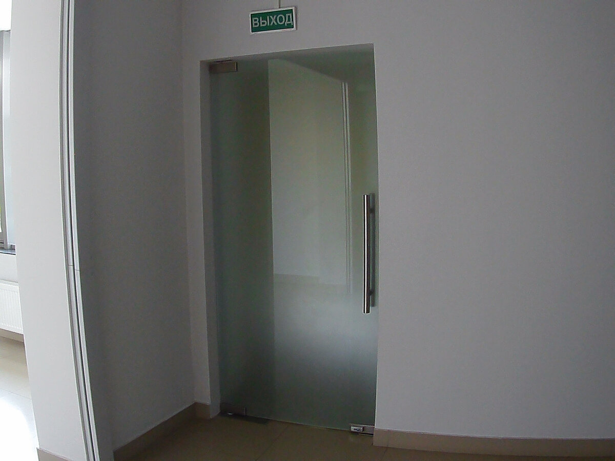 Маятниковая стеклянная дверь с доводчиком в клубном доме в Нижнем Новгороде. Бесцветное закаленное матовое стекло с химическим травлением matelux. Фурнитура фабричного качества с покрытием из нержавеющей стали.