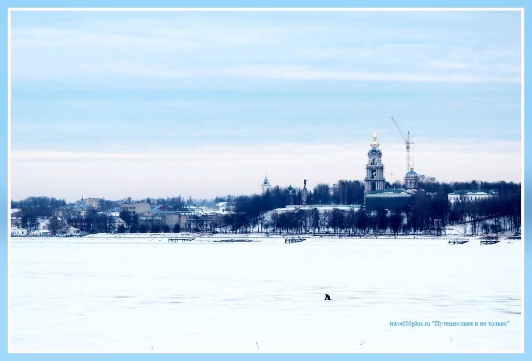 Рыбак, сидящий на середине реки Волги, на фоне центра города Костромы.