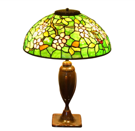 Прекрасная настольная лампа Tiffany Favrile из стекла и бронзы в виде цветов яблони, Tiffany Studios, Нью-Йорк, около 1910 года в стиле модерн. Куполообразный абажур из свинцового стекла с общим узором цветков яблони из розово-белого полосатого опалового стекла, листья и ветви в оттенках зеленого на фоне крапчатого зеленого стекла.