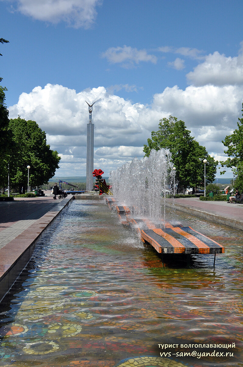 Вид на монумент Славы из сквера Победы (открыт в 1975 году), от 30-струйного фонтана (архитекторы В.Каркарьян, В.Борисов, художник Р.Баранов), символизирующего 30-летие Победы. Фото 17.05.2015.