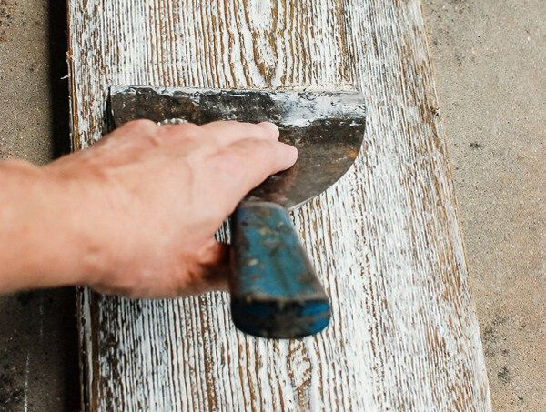 Вот так выглядит перекраска деревянной доски шпателем и белой краской. На фото удаляются излишки краски шпателем.