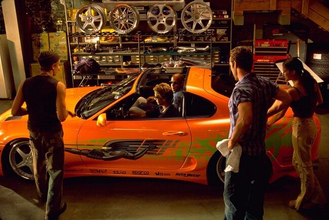 
 
Фильмы про гонки — своеобразный синоним «Форсажа». На экраны вышло уже  восемь частей приключений Доминика и его накаченной братии. Сейчас герои  намного реже гоняют на автомобилях ради скорости и кайфа. Куда уж там,  им ведь нужно мир спасать. Именно поэтому в нашем ТОПе оказалась первая  часть истории. В ней куда больше атмосферы и философии уличных  стритрейсеров.
 
Молодой полицейский Брайан помешан на автомобилях. Именно поэтому его  внедряют в автобанду некоего Доминика, который, по подозрению служителей  закона, осуществляет дерзкие ограбления. Брайан быстро становится своим  в банде, и вскоре его дружеские отношения с Домиником начинают мешать  осуществлению задания.
 
Первый «Форсаж» для многих стал своеобразным эталоном жанра. Здесь куда  меньше пафоса, зато присутствует драйв и обаятельные герои.