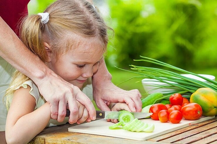 Многие мамы постоянно прогоняют своих маленьких дочек с кухни, чтобы не путались под ногами.  Уже в три года девочке вполне можно  доверить столовый или пластмассовый нож и показать как режут овощи.