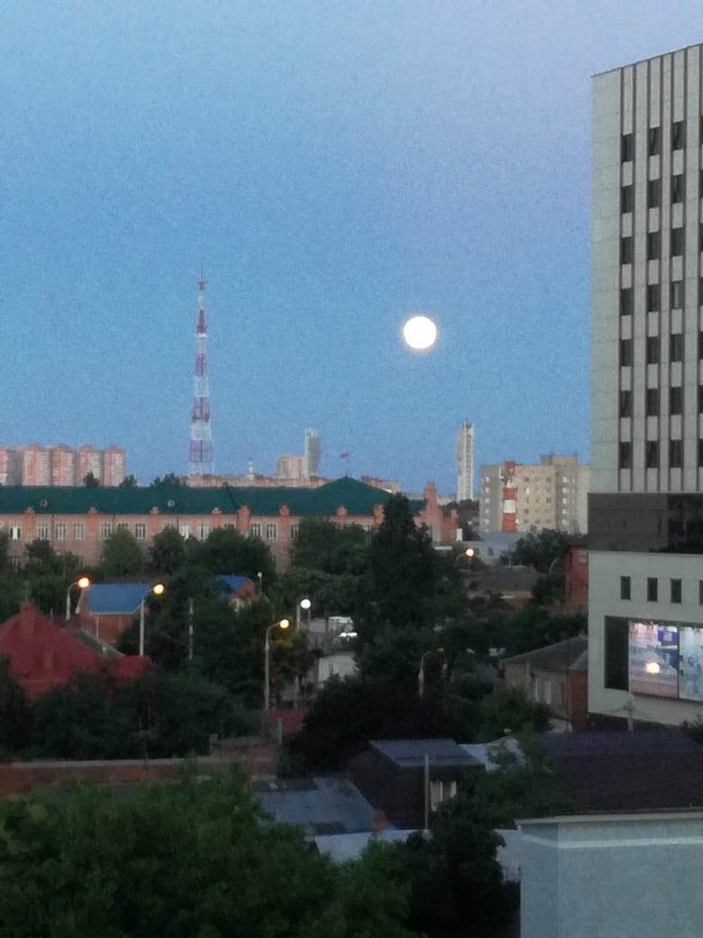 Фото подруги из окна её квартиры в центре на вечерний город и луну.