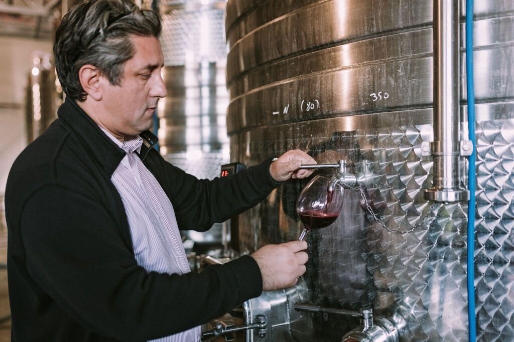 Фото сомелье сливает из чана вино в бокал