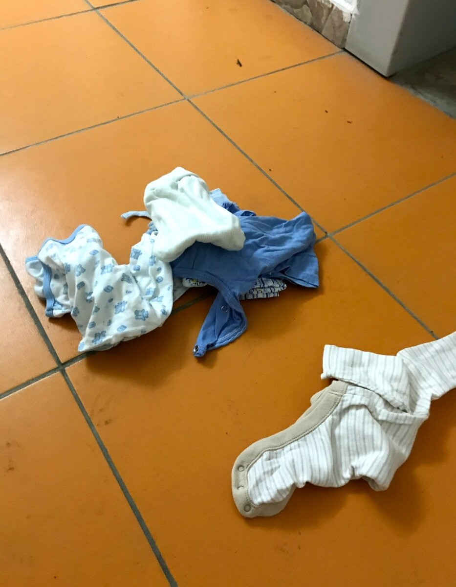 Детские вещи в подъезде на полу 