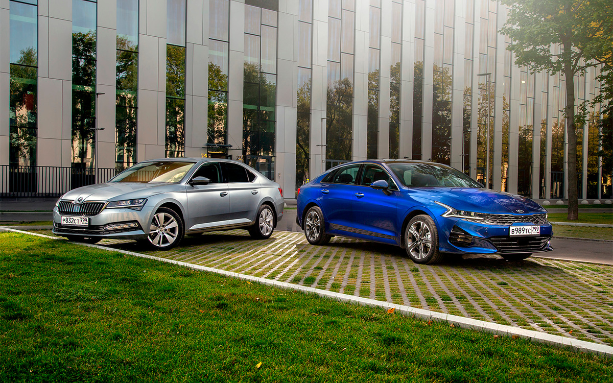 Цены на новые машины из-за рухнувшего рубля меняются так быстро, что в этом тесте мы решили обойтись без них. Просто представьте, что нужно выбрать: Kia K5 или Skoda Superb. Казалось бы, при чем здесь Toyota Camry? 
Фото: Вячеслав Крылов
В споре больших седанов D-класса Kia Optima почти вплотную приблизилась к вечному бестселлеру Toyota Camry, но есть ощущение, что имидж японской модели еще долго будет обеспечивать ей полноценное лидерство. Поэтому оставим ее за рамками этого теста и посмотрим, что может предложить яркий и очень свежий седан Kia K5 модели, которая лидирует в классе как минимум по практичности, то есть Skoda Superb. 
Мне всегда казалось, что люди устали от гегемонии Toyota Camry и должны с удовольствием смотреть на любую другую машину сопоставимых потребительских качеств, но авторынок так не работает. Camry имеет огромную лояльную аудиторию и имидж такой силы, что легко находит покупателей на первичном и вторичном рынках в любом возрасте и с внешностью любой степени скукоты. И вовсе не факт, что более современный, яркий и технологичный автомобиль способен подвинуть Camry с пьедестала даже с учетом того, что здесь и сейчас продается дешевле. 
Разве что только такой, как этот синий K5 в топовом исполнении GT-Line с его длинным капотом и внешностью а-ля лифтбек. На таком, пожалуй, ездил бы даже я, хотя формат большого седана от меня все-таки далек. Просто потому, что К5 не воспринимается тяжеловесным, не обязывает иметь живот пятого размера и не требует медлительной солидности от владельца. В нем вполне нормально смотрится водитель в модной футболке с подвернутыми брюками, и сама машина к тому же совсем не обязательно должна быть исключительно черной.

