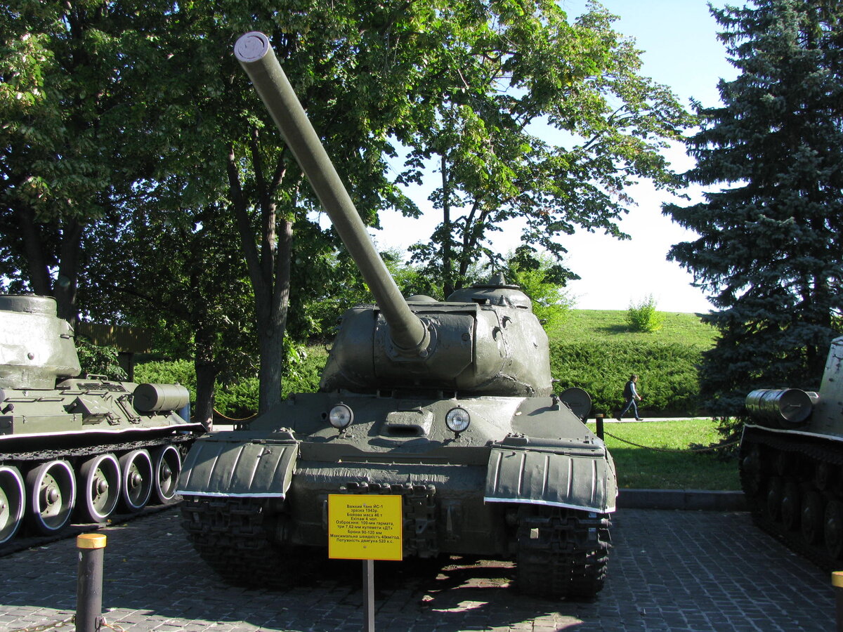 Тяжелый танк «Иосиф Сталин Первый» создавался в ответ на появление на Советско-германском фронте немецких тяжелых танков Pz.Kpfw.VI Ausf.E «Тигр», которые у нас обозначали Т-6. Но по воспоминаниям участников его разработки и военачальников тех времен, предназначался ИС-1 не для непосредственной борьбы с «Тиграми», а для решения тех же задач, что имели и они – для прорыва обороны противника, насыщенной мощными противотанковыми огневыми средствами.  На музейной табличке написано, что основное вооружение ИС-1 – калибра 100 мм, хотя в литературе значится 85-мм орудие Д-5Т, но была опытная модификация «Объект 248» со «стомиллиметровкой» С-34. С пушкой спарен 7,62-мм пулемет ДТ, еще один такой же встроен в лобовую часть корпуса
