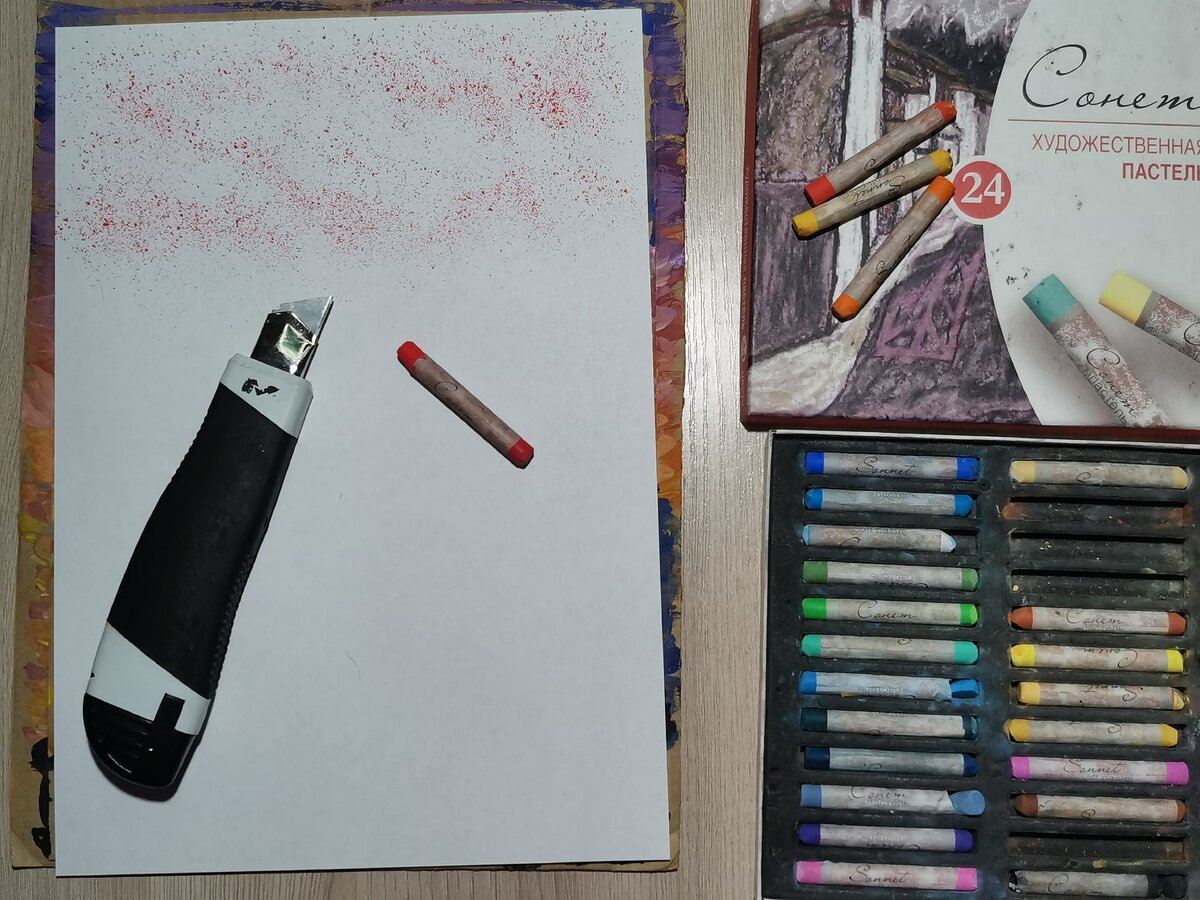 Теперь в верхней части листа покрошим бордовый цвет пастели с помощью канцелярского ножа.