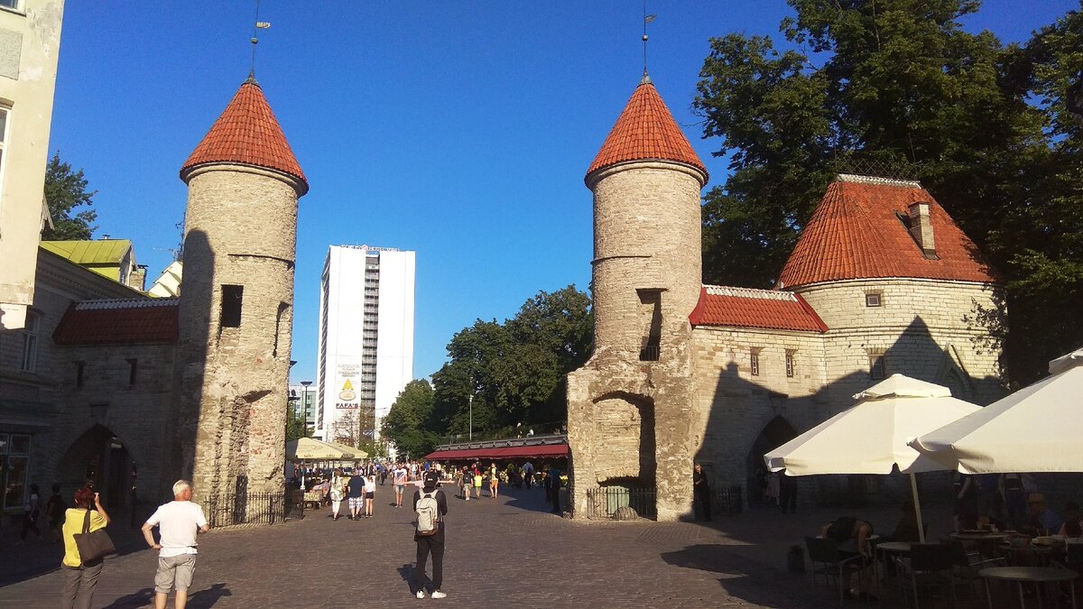 Ворота Виру или Вируские ворота. Старый город за моей спиной. Они находятся в начале улицы Виру поблизости от цветочного рынка - виден его коричневый козырек. Сами ворота не сохранились, но остался фрагмент оборонительной стены бастион и две башни с черепичными крышами, ставшие одним из узнаваемых символов Таллина. Кстати, эти башенки зарегистрированы в качестве товарного знака. У ворот очень богатая история, много раз их ломали, перестраивали. Это было связано с расширением дорог города. Но они смогли пережить все изменения и теперь радуют жителей и гостей города.
