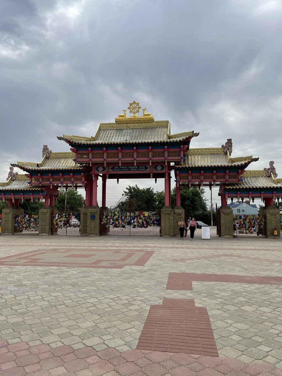 Вход в «Золотую обитель Будды Шакьямуни». На заборе разноцветные флажки.