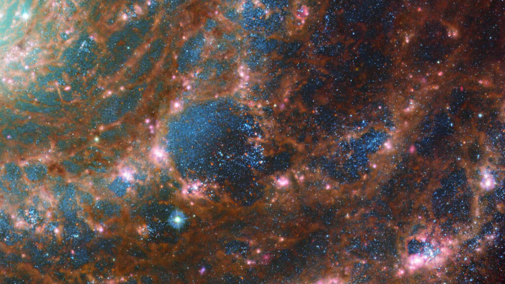    M74 shines at its brightest in this combined optical/mid-infrared image, featuring data from both the NASA/ESA Hubble Space Telescope and the NASA/ESA/CSA James Webb Space Telescope. The dust threaded through the arms of the galaxy is coloured red, and the young stars throughout the arms and the nuclear core are picked out in blue, by the James Webb Space Telescope’s Mid-InfraRed Instrument – MIRI. Meanwhile, the Hubble Space Telescope’s Advanced Camera for Surveys adds depth: the glow of the heavier, older stars towards the galaxy’s centre are primarily yellow, combined with the blue in this image to make a spooky green glow. The red bubbles of star formation are also visible in Hubble’s optical wavelengths. Scientists combine data from telescopes operating across the electromagnetic spectrum to truly understand astronomical objects. In this way, data from Hubble and Webb compliment each other to provide a comprehensive view of the spectacular M74 galaxy. Links Image A Image C Александр Шереметьев