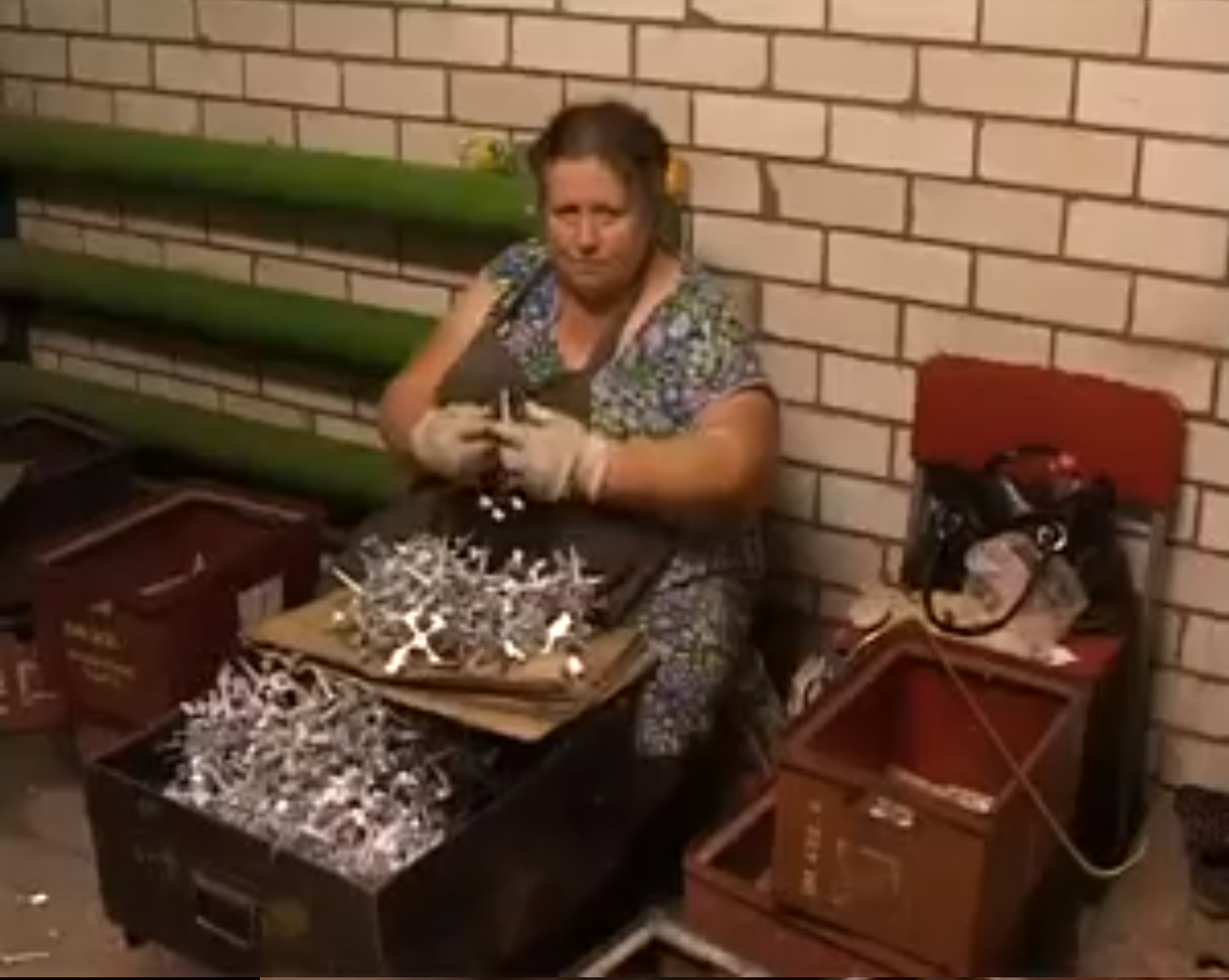 Некая женщина очищает кузова от крепного облоя.