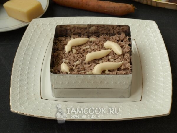 3. Нарезаем мелко говядину и смешиваем её с чесноком. Чеснок можно нарезать или выдавить через пресс. Выкладываем мясо сверху картошки и также смазываем майонезом.