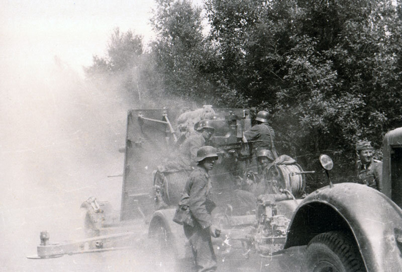 Боевая группа 58-ой пехотной дивизии, усиленная 8,8-см зенитной пушкой FlaK 37 из зенитного полка FlakRgt 36. на шоссе Псков-Гдов. На дороге, видимо, возникла ситуация, вызвавшая необходимость немедленно открыть огонь. Огонь ведется из походного положения, боковые упоры раскинуты, но не стабилизированы. / ПАИ