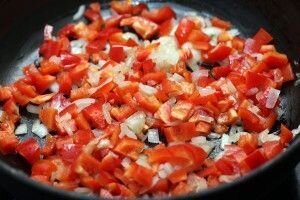     Перец и лук мелко нашинковать кубиками и обжаривать на раскаленной сковороде с добавлением масла. Как только лук приобретет золотистый цвет, огонь можно убавить. Теперь необходимо также мелко нарезать помидоры и добавить к нашим красивым овощам на сковороде.Тушим 5-7 минут на медленной огне.   