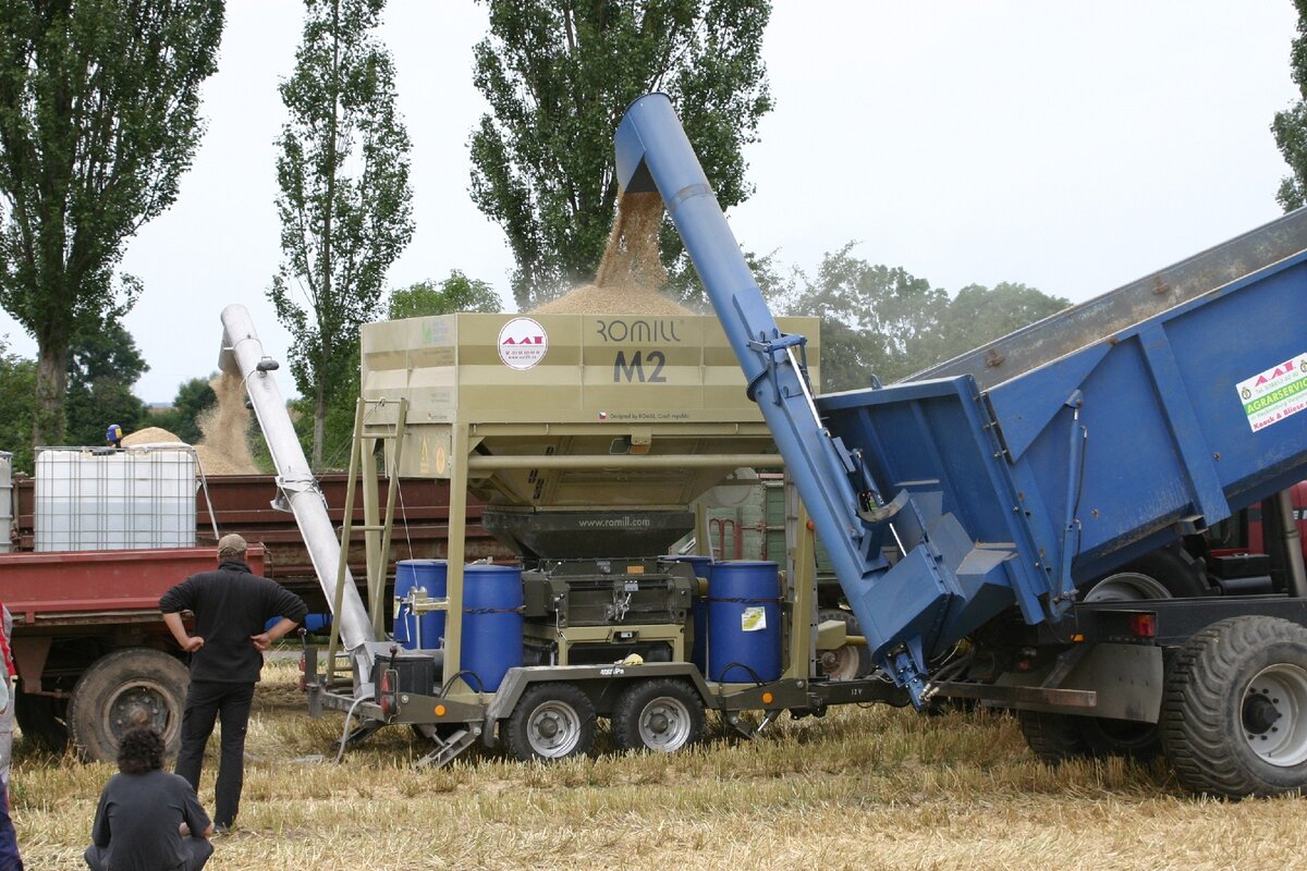 Плющилка ROmiLL  M 2 во время работы в поле. В левой части машины хорошо виден шнековый конвейер.