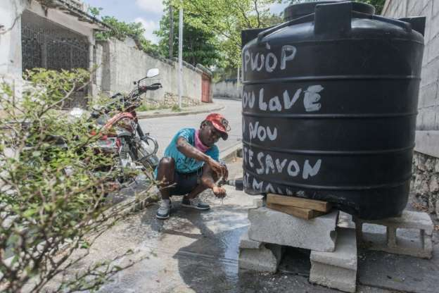 Портет-о-Пренс, местный водитель мотоцикла-такси моет руки