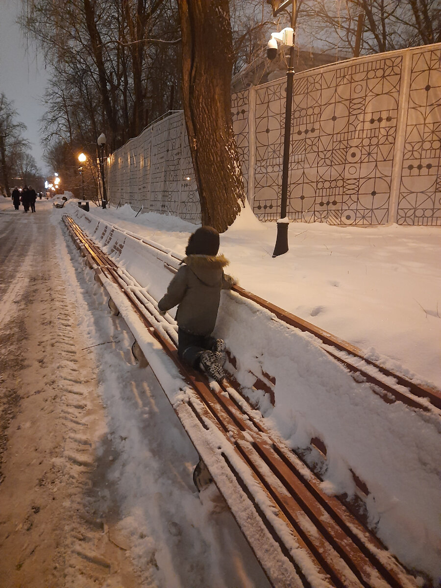 Сын очищает лавочку от снега в Парке Горького 