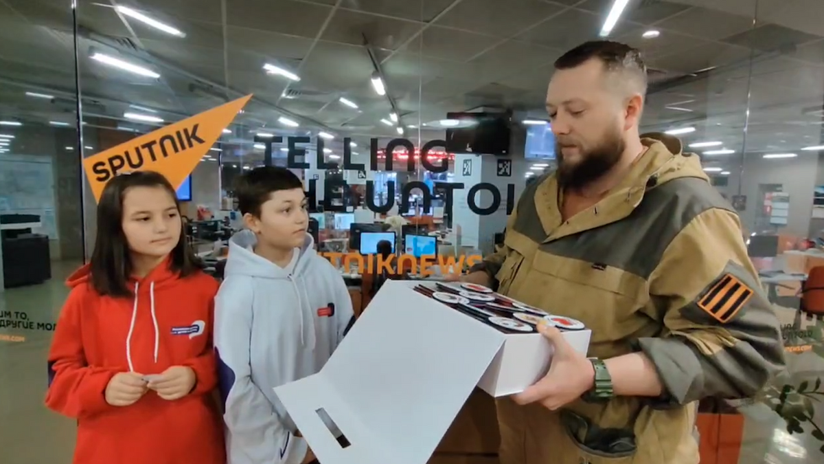    Корреспондент РИА новости принимает шевроны с рисунками детей для российских солдат© РИА Новости