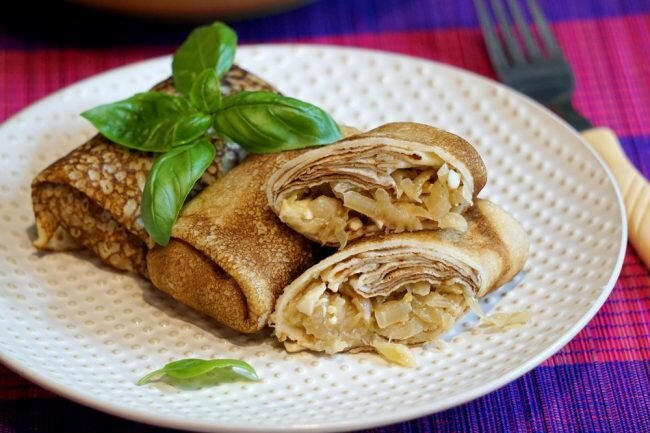 Фаршированные блины - это вкусный ужин для всей семьи, закуска на праздничный стол или сытный перекус на работе или в поездке. Это универсальное блюдо, к которому подходят как сладкие, так и несладкие начинки, нужно лишь регулировать количество сахара в тесте. Многообразие добавок к блинам практически бесконечно: варенье, сметана, сгущенное молоко, рыба, грибы, курица, икра - этот список можно продолжать долго. Очень вкусными получаются блинчики с капустой и яйцом, пошаговый рецепт с фото мы предлагаем Вам ниже.