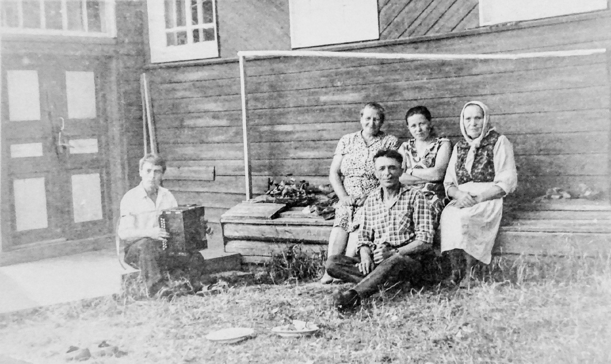 На завалинке бабушка, дедушка и родственники 
