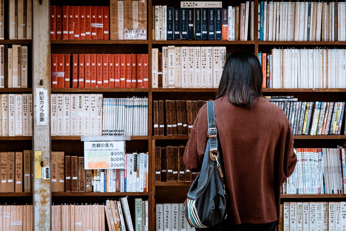 https://www.pexels.com/photo/woman-wearing-brown-shirt-carrying-black-leather-bag-on-front-of-library-books-1106468/X