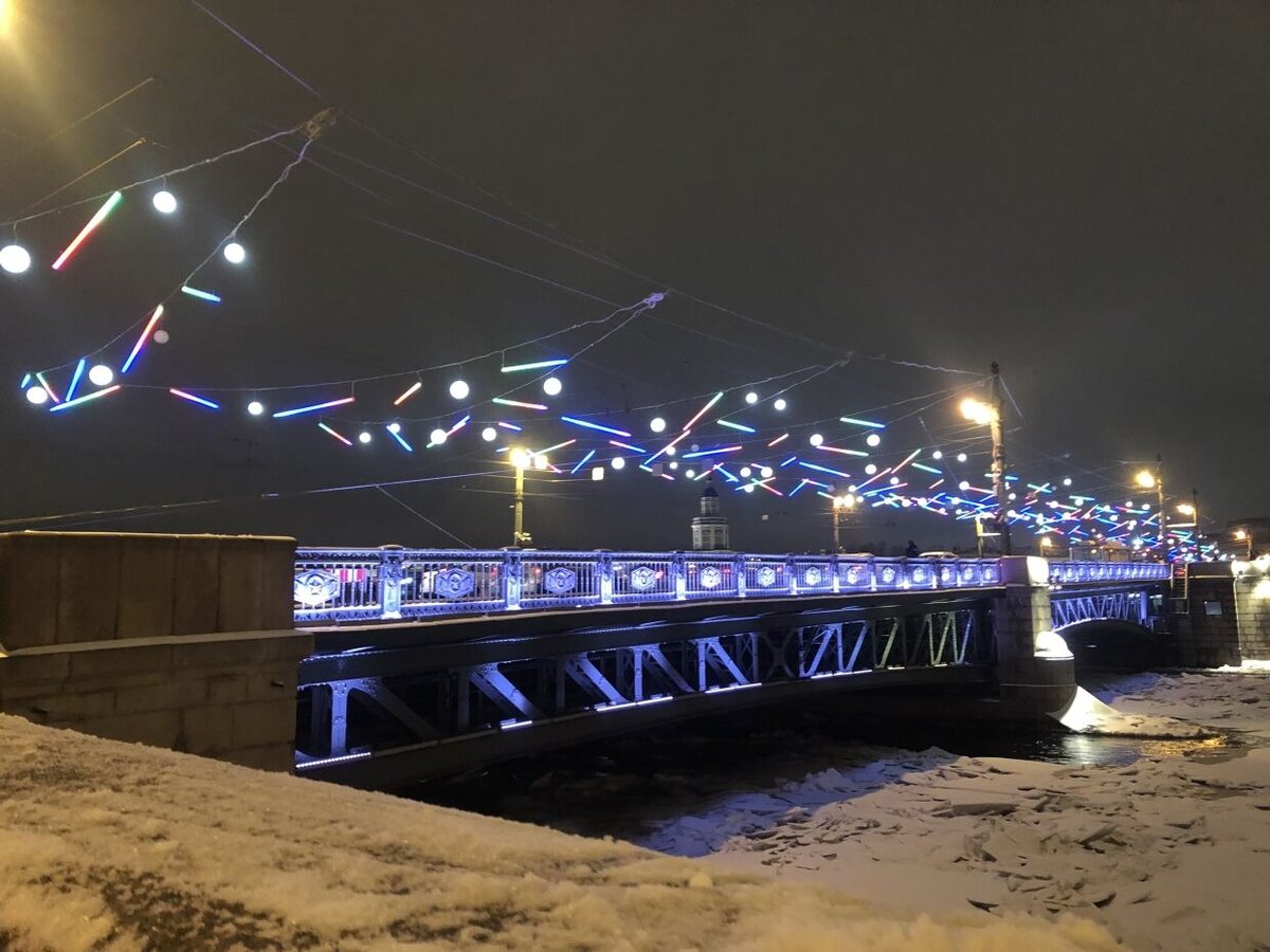 Новогоднее оформление появилось на Дворцовом мосту Северной столицы — светодинамическая композиция напоминает северное сияние. Настолько масштабный проект впервые реализован в России.