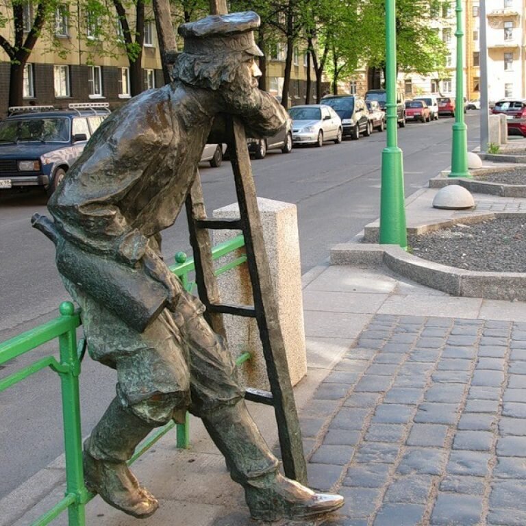 Городские скульптуры санкт петербурга. Памятник фонарщику в Санкт-Петербурге. Памятник фонарщику на Одесской улице. Памятник фонарщику в Петербурге. Одесская улица Санкт-Петербург фонарщик.