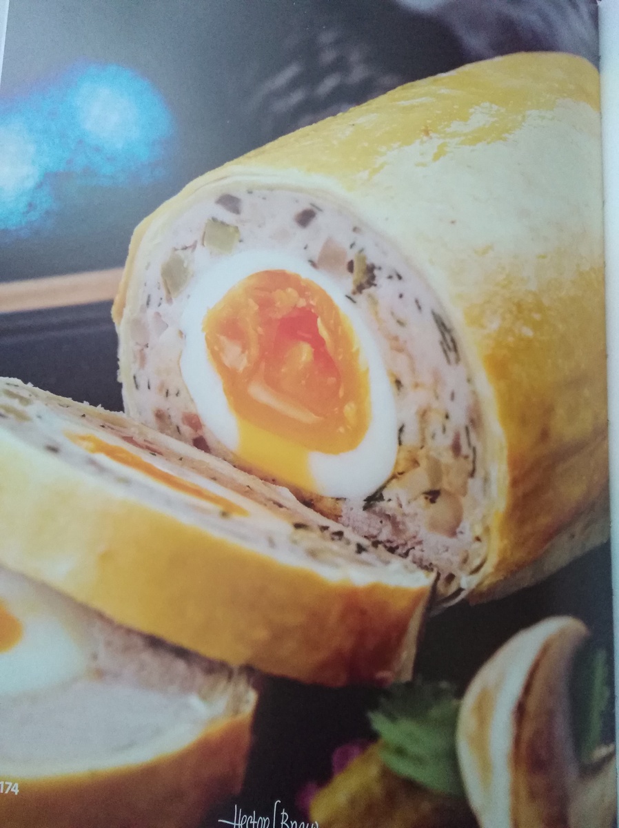 1.Робимо фарш зі свинини та курячого філе.Дрібно нарізаємо шампіньйони,цибулю,бекон та обсмажуємо на олії.Охолоджуємо,змішуємо з фаршем.Подріблюємо часник,огірки та кінзу.Додаємо до фаршу овочі та бекон,сіль,перець,та одне сире яйце.2.На харчову плівку викладаємо фарш шаром приблизно 2 см,у середину—варені в мішечок яйця.Замочуємо рулет навколо яєць.Відправляємо в холодильник на годину.3.Розкатуємо шар витяжного тіста,викладаємо на нього рулет і також загортаємо.Змащуємо тісто жовтком та запікаємо в духовці 40 хвилин при температурі 165°С 