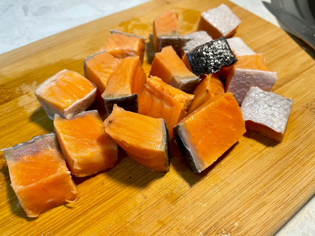 Очищаю от чешуи стейк красной рыбы и режу на кусочки