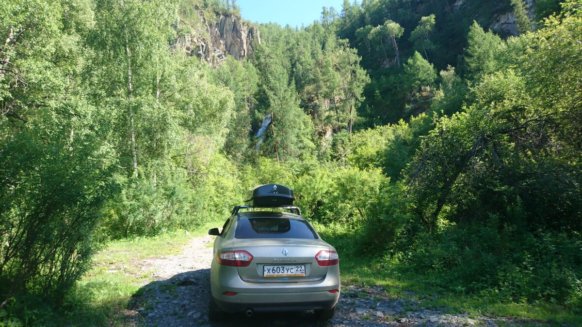 Водопад прячется в зелени деревьев.