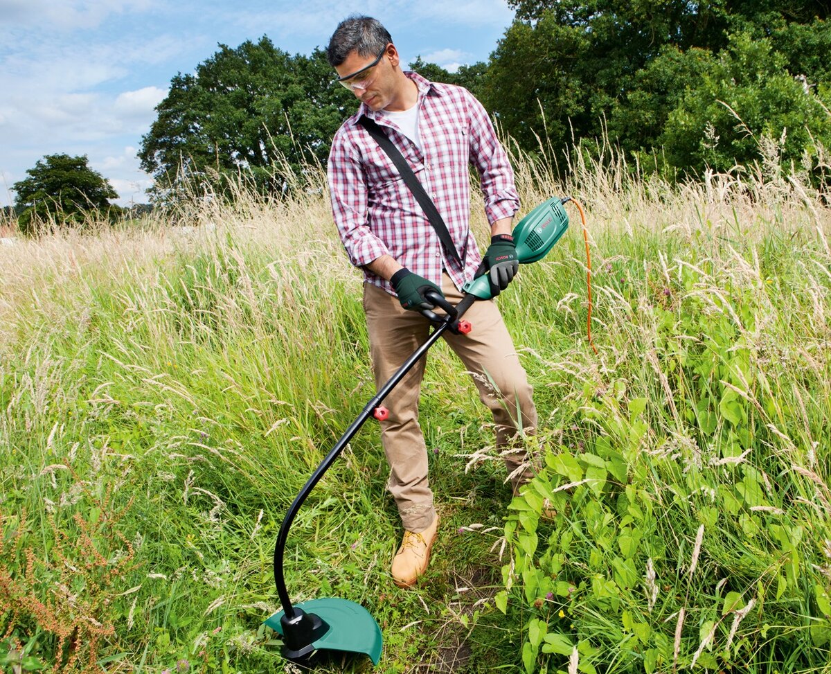 Процесс кошения электрическим триммером.   Из открытых источников.