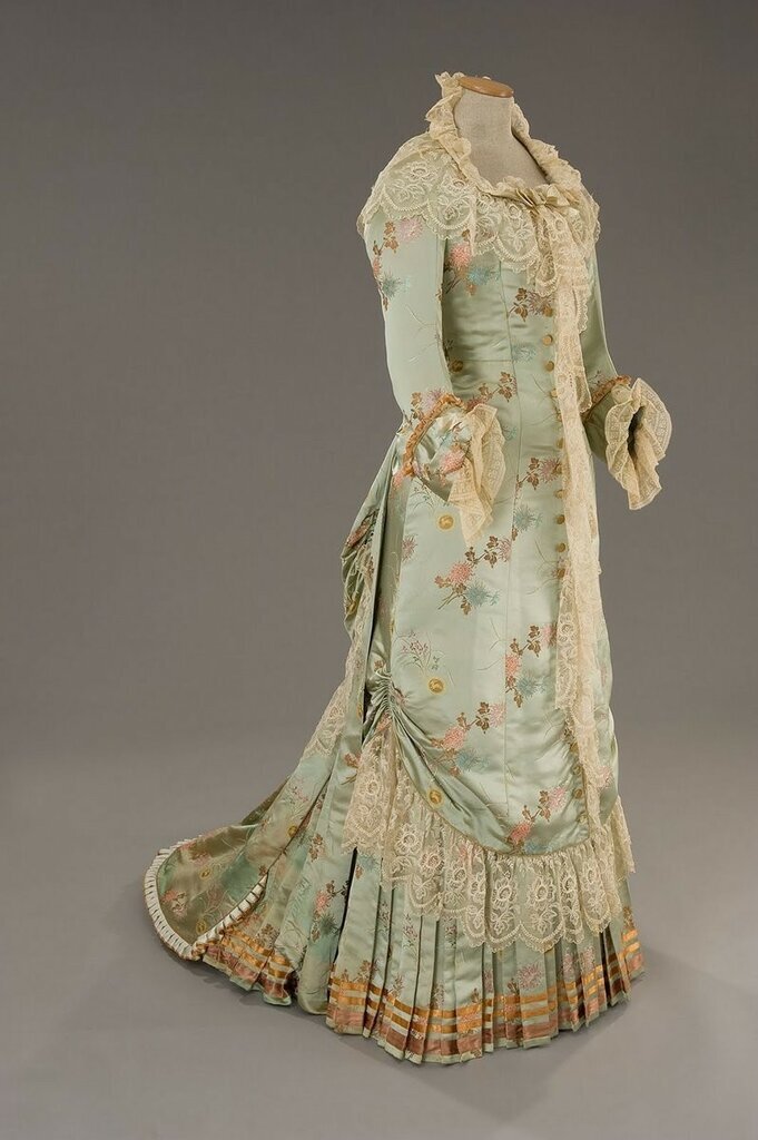 Домашнее платье (я бы добавила: кроя "принцесс", т.е. неотрезное по талии) из шелкового сатина цвета зеленой воды с розовыми, нежно-голубыми, золотистыми и сиреневыми цветами. Отделано старинными кружевами. https://tirellicostumi.com/collaboratore/abito_oscar/l_eta_dell_innocenza_29
