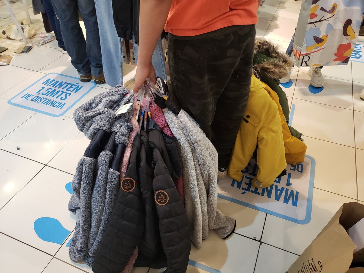 Мальчик в очереди на оплату, купил по нескольку одинаковых курток