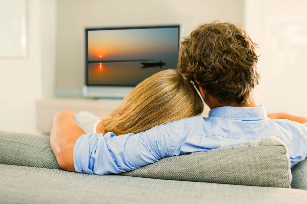 Муж смотрит ютуб. Перед телевизором. Человек перед телевизором. Пара на диване перед телевизором. Мужчина и женщина на диване в обнимку.