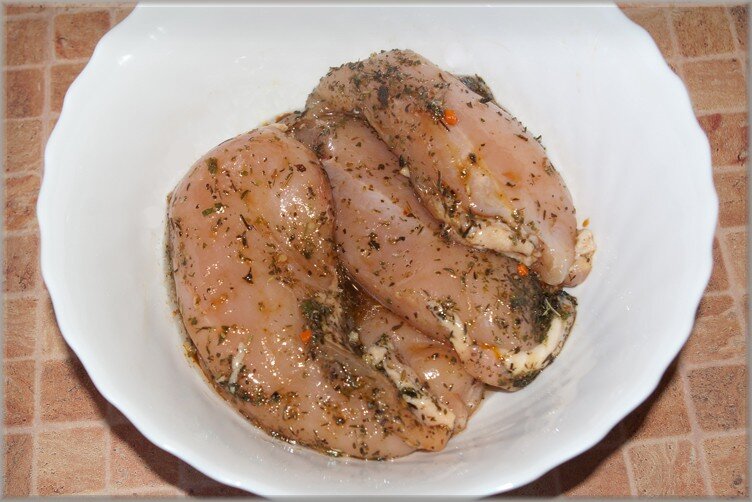 Каждую филейную часть разрезаем вдоль, так чтобы получилось два пласта — итого четыре. В пиале смешиваем 2 ложки масла и выбранные специи, перемешиваем. Полученной смесью хорошо натираем курицу со всех сторон и оставляем мариноваться на 15-20 минут. Куриное мясо очень нежное, по этому маринад быстро проникает в слои и напитывает будущие рулетики ароматом. 