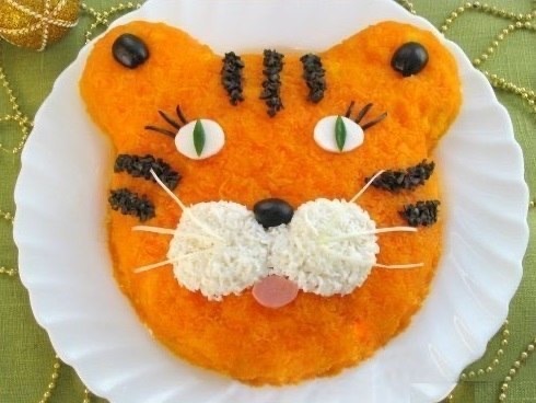 
🐯 Салат "Тигренок"
Ингредиенты: картофель - 400 гр, вареная колбаса - 200 гр, огурцы - 200 гр, лук-порей или репчатый лук - 150 гр, яйца - 3 шт, морковь - 400 гр, майонез, соль, маслины (для украшения).
Готовим: Картофель и морковь отвариваем до готовности, остужаем, чистим. Картофель и морковь натираем на мелкой терке. Колбасу и огурцы нарезаем мелкими кубиками. Лук-порей мелко крошим (репчатый лук нарезаем кубиками, заливаем кипятком, оставляем на 15 минут, затем промываем в холодной воде). Яйца варим вкрутую, остужаем, чистим и натираем на мелкой терке (белок от одного яйца оставляем для украшения).
На дно плоского блюда выкладываем картофель, придаем форму головы тигра и смываем майонезом. На картофель выкладываем слоями, смазывая каждый слой майонезом и подсаливая, следующие ингредиенты: вареная колбаса, огурцы, лук, яйца. Последним слоем выкладываем морковь, покрывая весь салат.
Из яичного белка делаем глазки и щечки тигренка. Мелко нарезаем около 6-7 маслин. Делаем из них нос и ресницы. Из огурца - зрачки. Из колбасы - рот. Из оставшихся нарезанных маслин выкладываем полоски. Усы можно сделать из белой части лука порея.
Приятного аппетита!