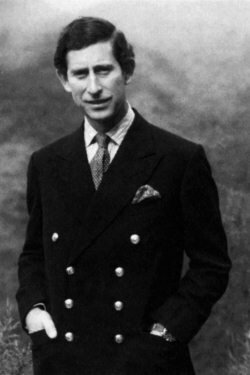 Принц Чарльз заложил руки в карманы, но при этом демонстрирует большой палец
