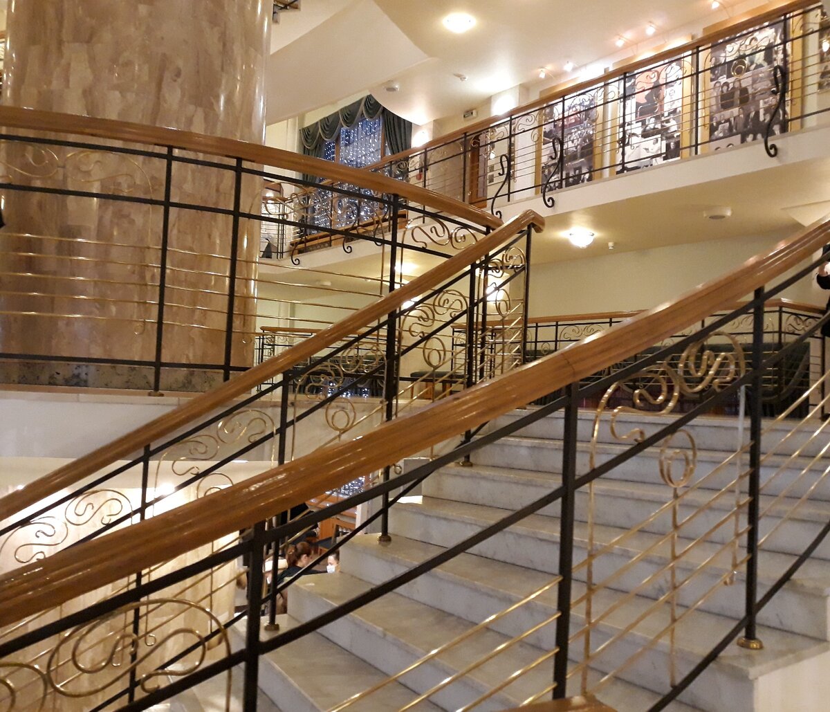 Это фото - выходная (или входная )! ) ария театра Новая опера. Такой он и есть:  витые золотые переплетения металла, светлый тон камня, приглушенное дерево перил, дверей и перегородок.